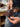 Hands threading a leather belt through the slots of a dark brown pocket knife sheath