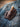Trapper pocket knife seated in a dark brown leather belt sheath, laid on a denim jacket
