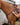 Rider buckling the tug strap of the pink buckstitch breast collar to the saddle D-ring on a sorrel horse beside a horse trailer