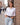 Woman styling the purple buckstitch western belt with a white shirt and light jeans on a city street